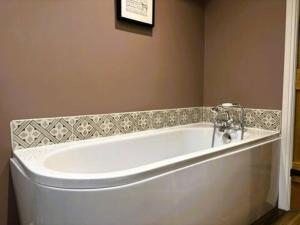 une baignoire blanche dans une salle de bain avec un mur dans l'établissement The Cottage at Sychnant Farm, à Talgarth 30 autres photos