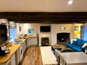 Il comprend une cuisine et un salon doté d'un canapé bleu. dans l'établissement The Cottage at Sychnant Farm, à Talgarth