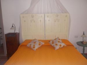 een slaapkamer met een oranje bed met 2 kussens bij Appartamento Girasole Seaside and Pool in La Caduta