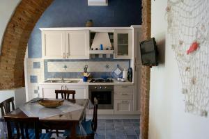 een keuken met witte kasten en een tafel met stoelen bij Appartamento Lavanda Seaside and Pool in La Caduta