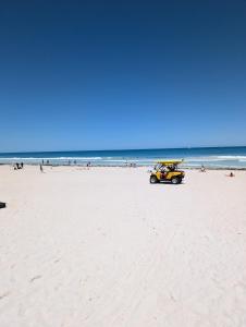 a yellow car on a beach with people in the ocean at 5BR Beachside Home with Pool, Park Access in Perth