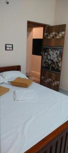 ティルヴァンナーマライにあるGuru Roomsのベッドルーム(白いベッド1台、木製の棚付)