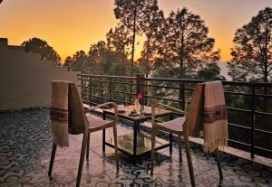 a table and chairs on a balcony with a sunset at ilika Resort - A Boutique Stay 30 km from Devprayag in Pauri