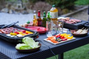 高岛市和風グランピング LYS AIBA House 一 わんちゃんと泊まれる一棟貸古民家一Japanese Style Glamping Dog Friendly Private Villa的一张野餐桌上摆放着几盘食物和几瓶酒。