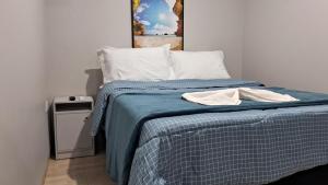 a bedroom with a bed with a blue comforter at Suíte Harmonia 4 in Campo Grande