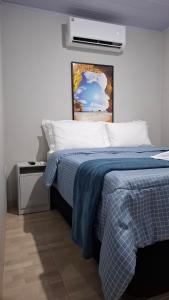 a bedroom with a bed with a blue and white blanket at Suíte Harmonia 4 in Campo Grande
