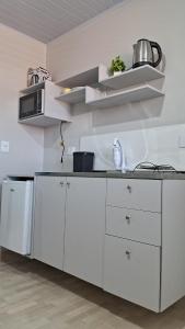 a kitchen with white cabinets and a microwave at Suíte Harmonia 4 in Campo Grande