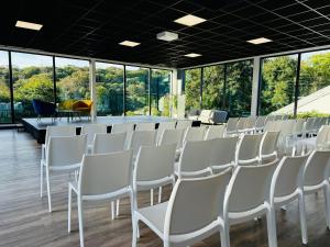 eine Reihe weißer Stühle in einem Zimmer mit Fenstern in der Unterkunft KoonTy - Chambres et Appartements à Landerneau in Landerneau