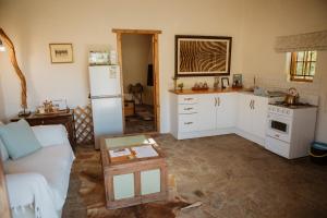cocina con sofá y nevera en Wild Olive Cottage, en Graaff-Reinet