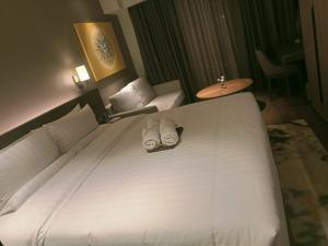 a bedroom with a large white bed with two slippers at Cleo Suites at Novotel Hotel Residences near Makati in Manila