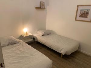 two beds in a room with a lamp on a table at Maison avec jardin, à deux pas de Paris in Deuil-la-Barre