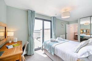 a bedroom with a bed and a desk and a window at 12 Middlecombe - Luxury Apartment at Byron Woolacombe, only 4 minute walk to Woolacombe Beach! in Woolacombe +31 photos