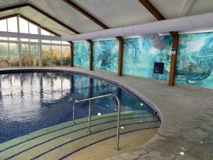 a large swimming pool in a building with a mural at H05 Par Sands in Tywardreath