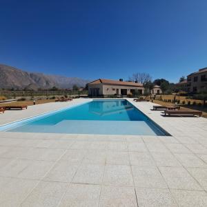 a swimming pool with benches and mountains in the background at Apart entre viñas in Cafayate