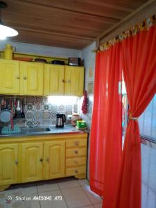 eine Küche mit gelben Schränken und einem roten Vorhang in der Unterkunft La casita de Marga in Concordia