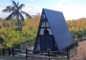 a small house with a black roof and a palm tree at Chalé Amorata in Ibirama