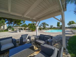 un padiglione con divani e sedie di fronte a una piscina di Resort Villa Hermosa a Porto Cesareo