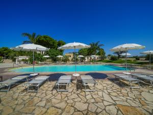 una piscina con tavoli, sedie e ombrelloni di Resort Villa Hermosa a Porto Cesareo