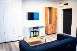 ein Wohnzimmer mit einer blauen Couch und einem Fernseher in der Unterkunft Urban76 Apartments in Târgu Mureș