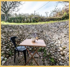 a table and chair in front of a rock wall at Chez Anaïs I T1 I Sauverny in Sauverny