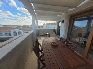 a porch with a wooden table and chairs on a balcony at H41 Attico in centro in Budoni +10 photos