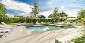 Schaelsbergerbosch Eco - Garden House Sauna copy في بيرغ إين تيربيلييت: حمام سباحة مع كراسي وطاولات بيضاء ومنزل