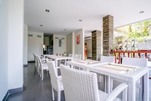 a dining room with white tables and white chairs at Kamini Legian Hotel in Legian