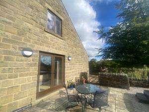 伊姆Hollow Brook Cottage Heart of the Peak District的建筑物旁边有一张桌子和椅子的露台
