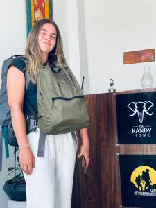 a woman with a backpack standing next to a booth at The Kandy Home & City mirror Hostel in Kandy
