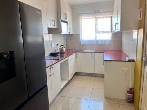 a kitchen with white cabinets and a black refrigerator at SNE Travellers in Faure