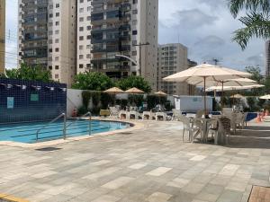 a pool with tables and chairs and umbrellas at Eldorado Thermas Park Localização Top área de Lazer Completa in Caldas Novas