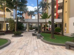 a courtyard with benches and palm trees in a building at Eldorado Thermas Park Localização Top área de Lazer Completa in Caldas Novas