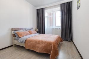 ein Schlafzimmer mit einem Bett mit einer orangefarbenen Decke und einem Fenster in der Unterkunft Апартаменты в ЖК Ирина рядом с Баянтау in Pawlodar