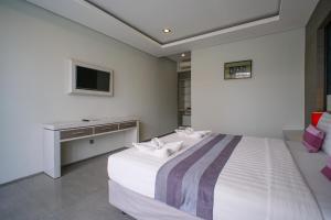 a bedroom with a bed and a desk and a television at Kamini Legian Hotel in Legian