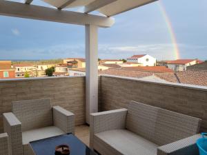 Un balcón con dos sillas y una mesa y un arcoíris. en H41 Attico in centro, en Budoni
