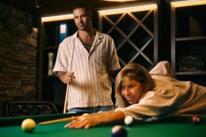 a man standing next to a woman playing pool at Peaks Place Apartments & SPA in Laax