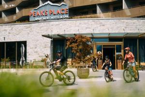 a group of people riding bikes in front of a building at Peaks Place Apartments & SPA in Laax