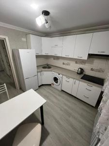 a kitchen with white cabinets and a washer and dryer at Buiucani in Chişinău