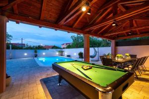 einen Billardtisch in der Mitte einer Terrasse mit Pool in der Unterkunft Villa Renata ZadarVillas in Zaton