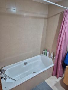 La salle de bains est pourvue d'une baignoire avec un rideau de douche rose. dans l'établissement Donna Olympia's House, à Sucina