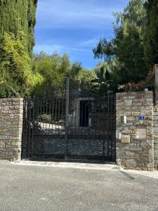 een zwarte metalen poort met een stenen muur bij Villa Terra Alba in Le Lavandou