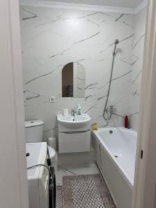 PrigorodnyyKvartira Astana的白色的浴室设有水槽、浴缸和卫生间。