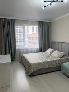 PrigorodnyyKvartira Astana的一间卧室，里面有一张床和一扇大窗户。