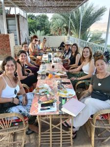 un grupo de personas sentadas alrededor de una mesa larga en Rayan Nubian Guest House, en Asuán