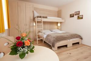 a small bedroom with a bunk bed with flowers on a table at Landhotel Schustermühle in Seefeld-Kadolz