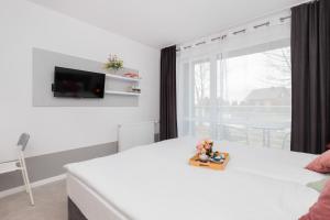 Un dormitorio con una cama blanca y un televisor en la pared. en Unique Studio with Balcony in Jastrzębia Góra by Noclegi Renters, en Tupadły 8 fotos más