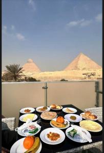 una mesa llena de comida con pirámides en el fondo en Aurum Pyramids View, en El Cairo