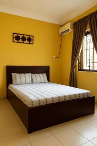 a bed in a room with a yellow wall at Dumeros in Abuja