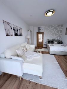 ein Wohnzimmer mit einem weißen Sofa und einem Bett in der Unterkunft Chiemsee-Perle, stylisches Luxus-Appartement in Rimsting