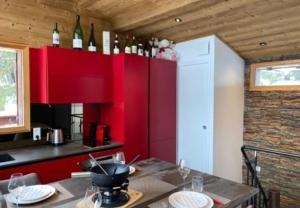 a kitchen with red cabinets and a table with wine bottles at Chalet Cosy in Pugny-Chatenod